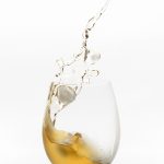 Gelbe Flüssigkeit mit Eiswürfeln im Weinglas